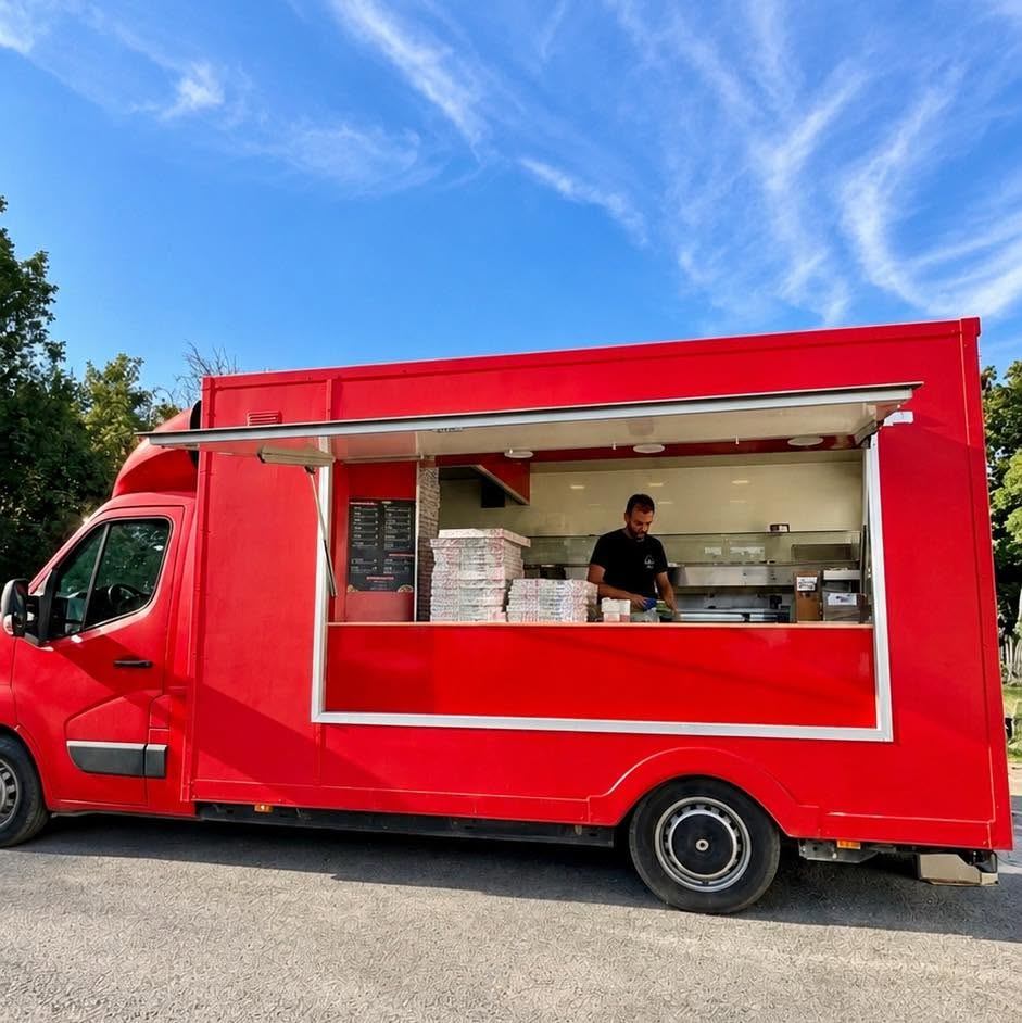 Le camion rouge du Four à Pizz', guichet ouvert sous un ciel bleu