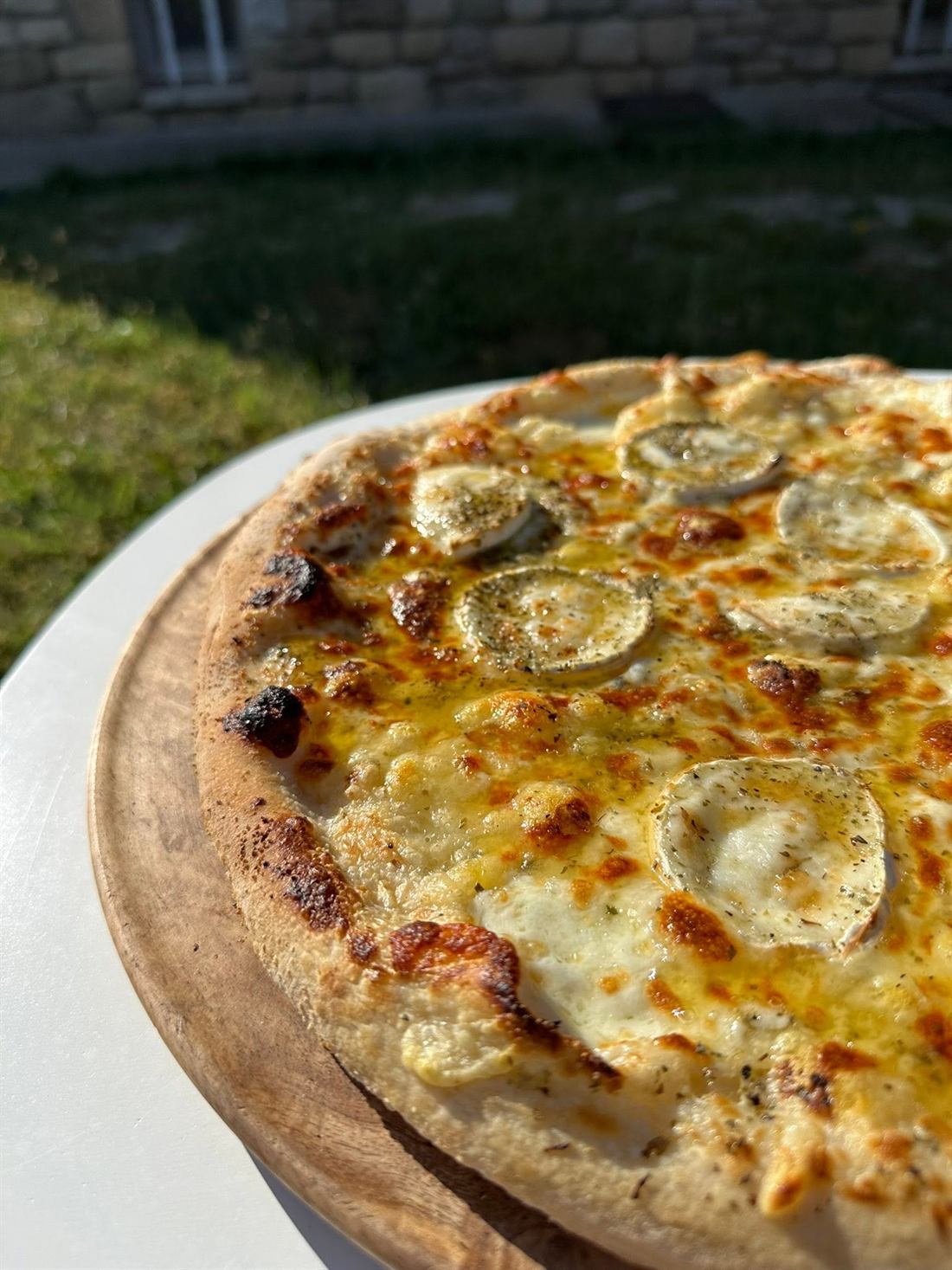 Pizza chèvre miel du Four à Pizz', croûte dorée, posée sur sa planche en bois